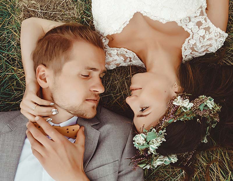 Brautpaar liegt verliebt auf einer Wiese während der Hochzeit