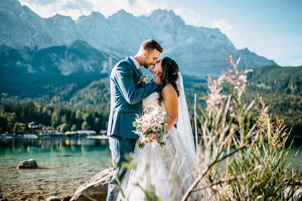 Hochzeitspaar küsst sich vor Alpenkulisse am Eibsee