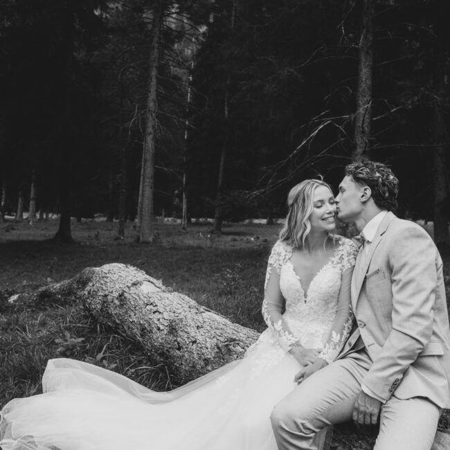 Romantic summer wedding couple in the forest in Garmisch — groom kissing bride on the cheek during an intimate photoshoot planned by AWIKA WEDDINGS.