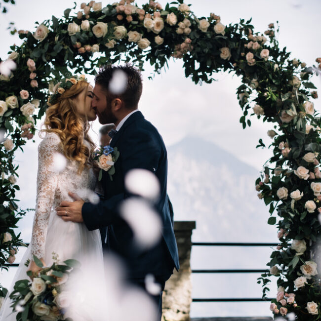 Romantic wedding ceremony beneath a floral arch during an elegant alpine destination wedding