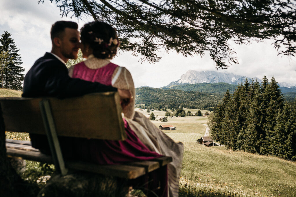 couple sitting in alpine meadow overlooking mountain landscape during wedding