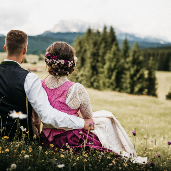 couple sitting in alpine meadow with mountain view wedding moment